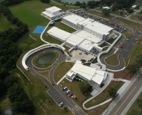 Modern school campus with state-of-the-art site development, extensive parking, sports facilities, and landscaped areas, emphasizing professional site planning and construction.
