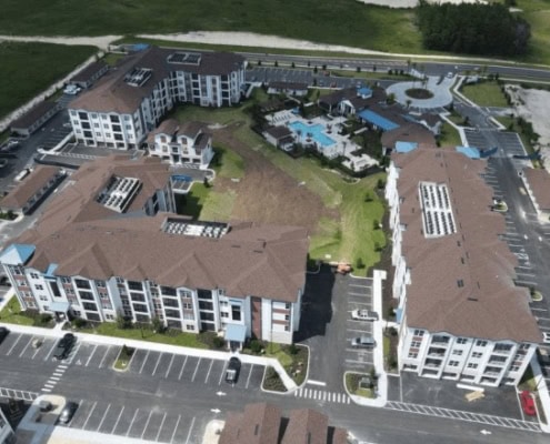 Modern multi-story residential apartment complex with sustainable site development and extensive parking facilities.