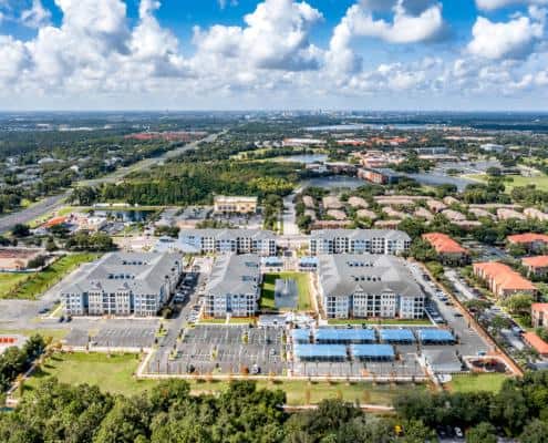 Modern apartment complex with parking lot, water feature, and surrounding greenery - Example of site development for residential communities.