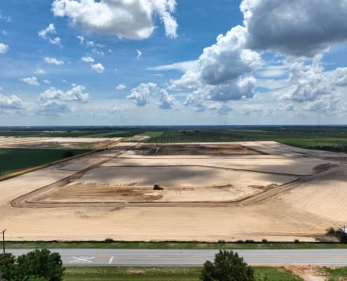 Clear construction site with land development and site improvement, showcasing earthwork for new infrastructure, in a rural area under a partly cloudy sky.