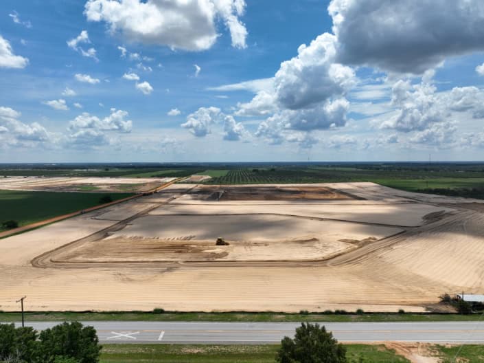 Clear construction site with land development and site improvement, showcasing earthwork for new infrastructure, in a rural area under a partly cloudy sky.