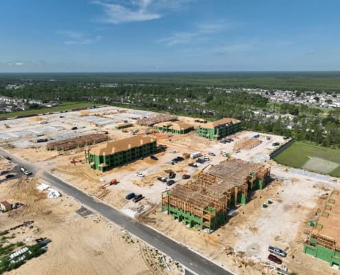 Modern residential construction site featuring multi-family apartment buildings in progress, showcasing framing, foundation work, and active development.
