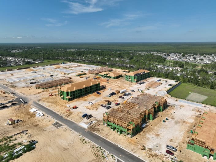 Modern residential construction site featuring multi-family apartment buildings in progress, showcasing framing, foundation work, and active development.