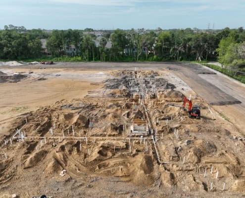 Excavation site for new commercial building with plumbing and foundation pipes installed, showcasing site development and construction progress.