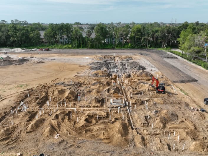 Excavation site for new commercial building with plumbing and foundation pipes installed, showcasing site development and construction progress.