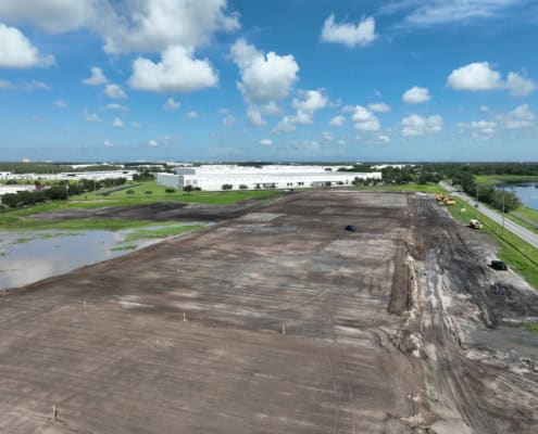 Empty lot under construction with machinery and vehicles, preparing for site development and building.