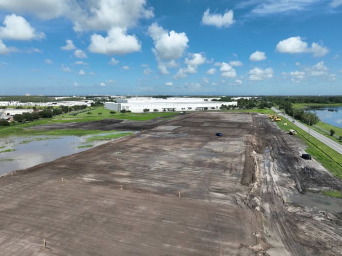 Empty lot under construction with machinery and vehicles, preparing for site development and building.