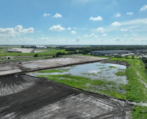 Empty land and construction site at SDC Site Development project with water pond and cleared earth for commercial development.