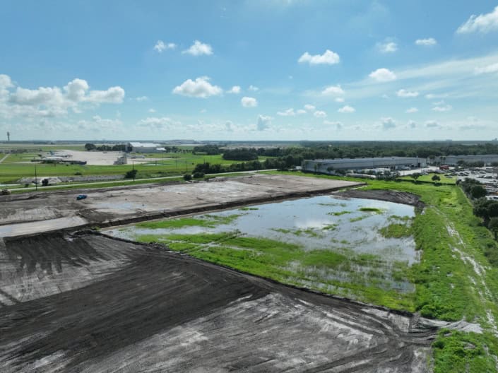 Empty land and construction site at SDC Site Development project with water pond and cleared earth for commercial development.