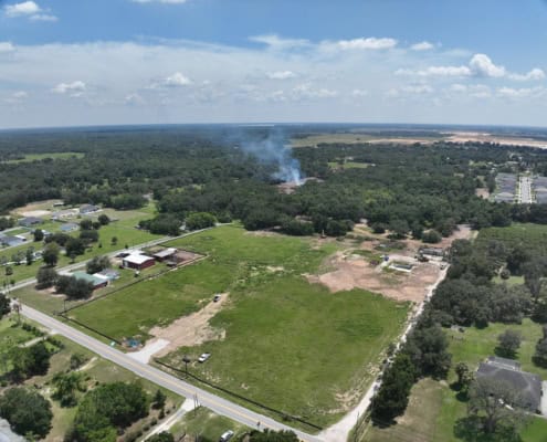 Aerial view of land development project with site preparation and construction in progress for new residential or commercial buildings in a suburban area.
