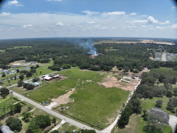 Aerial view of land development project with site preparation and construction in progress for new residential or commercial buildings in a suburban area.