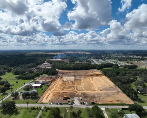 Excavation site for commercial development with heavy machinery and cleared land, showcasing site development, land grading, and preparation for construction projects in a suburban area, Florida.