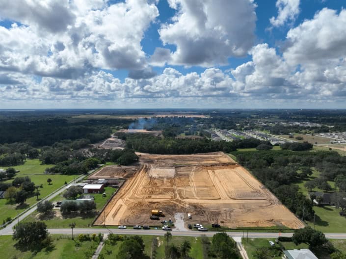 Excavation site for commercial development with heavy machinery and cleared land, showcasing site development, land grading, and preparation for construction projects in a suburban area, Florida.