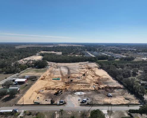 Clear construction site for commercial development with heavy machinery and land preparation, showcasing site development, excavation, and planning for a new business facility.