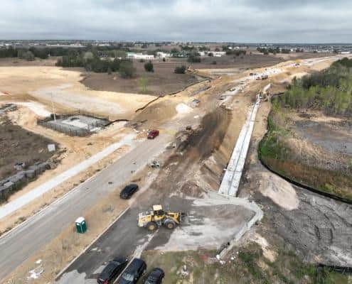 Construction site for commercial development with earthmoving equipment and infrastructure work underway.
