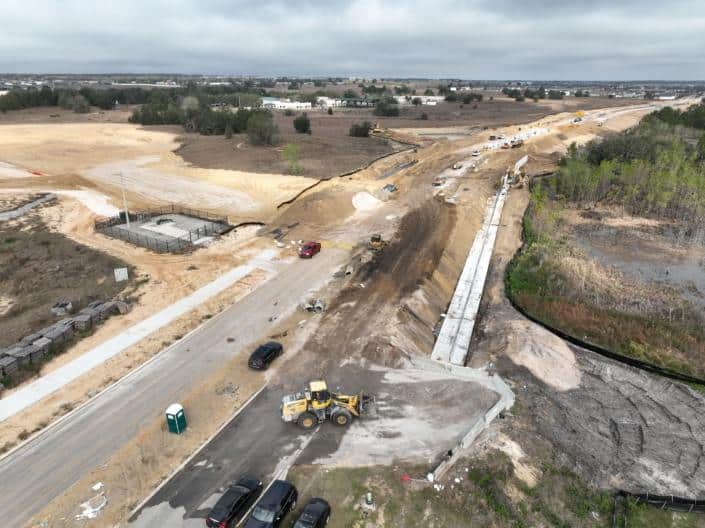 Construction site for commercial development with earthmoving equipment and infrastructure work underway.