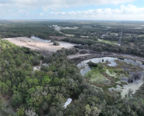 Aerial view of construction site with wetlands and trees, showcasing development and site preparation for sustainable infrastructure projects.