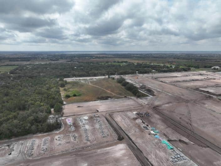 Aerial view of the early stages of site development for a commercial or industrial project, showcasing land clearing, grading, and construction preparation for infrastructure.