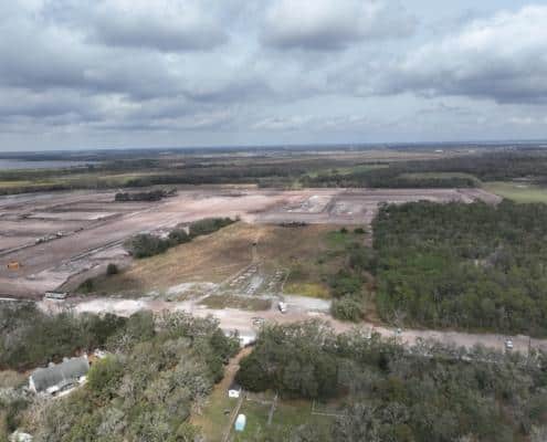 Extensive site development in progress showcasing land clearing, grading, and construction for new commercial or industrial development with a natural landscape background.