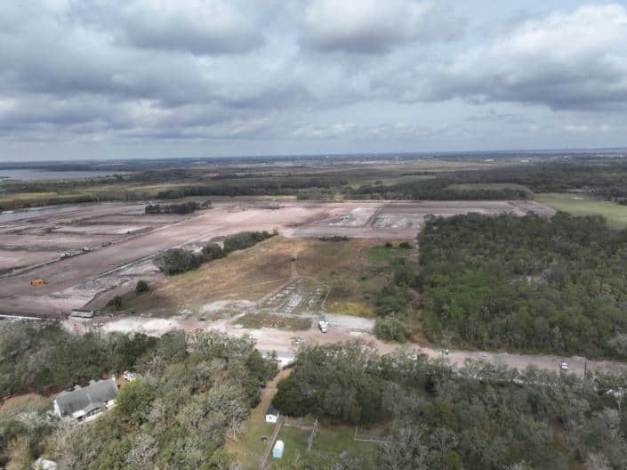 Extensive site development in progress showcasing land clearing, grading, and construction for new commercial or industrial development with a natural landscape background.