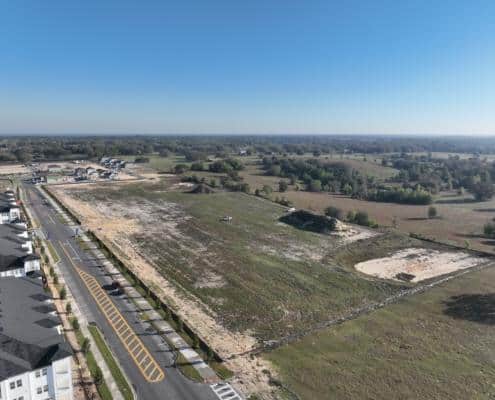 Vacant land for commercial development with nearby residential neighborhood and open green space, ideal for site development, construction, and urban planning.