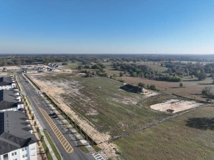 Vacant land for commercial development with nearby residential neighborhood and open green space, ideal for site development, construction, and urban planning.