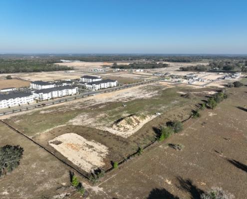 Aerial view of a new residential development site with ongoing construction, open plots, and surrounding landscape, showcasing site development and infrastructure progress.