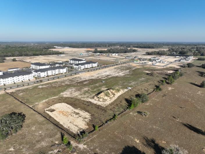 Aerial view of a new residential development site with ongoing construction, open plots, and surrounding landscape, showcasing site development and infrastructure progress.
