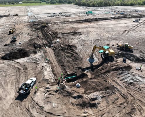Excavation site with heavy machinery and construction workers creating foundation for a new development project.