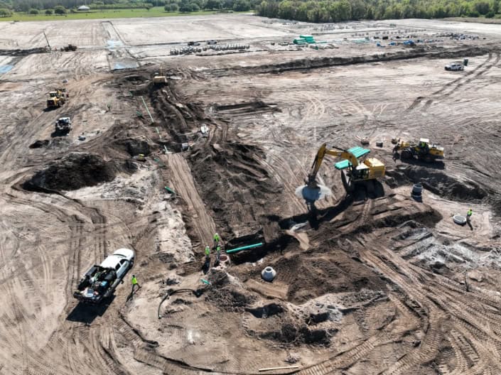 Excavation site with heavy machinery and construction workers creating foundation for a new development project.