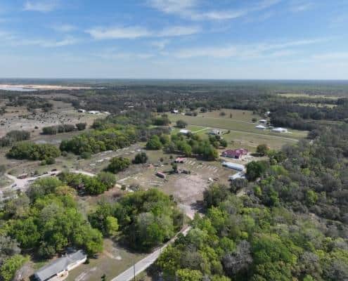 Vast rural land with green trees, open fields, and scattered buildings showcasing site development in Florida.