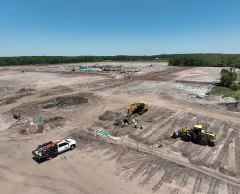Excavation site for commercial construction with heavy machinery and construction workers, preparing land for development.