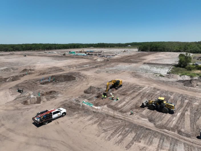 Excavation site for commercial construction with heavy machinery and construction workers, preparing land for development.
