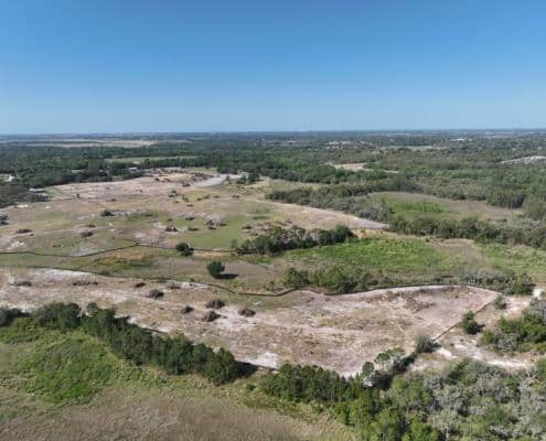 Aerial view of large undeveloped land for commercial or residential site development in Florida with open fields and trees.