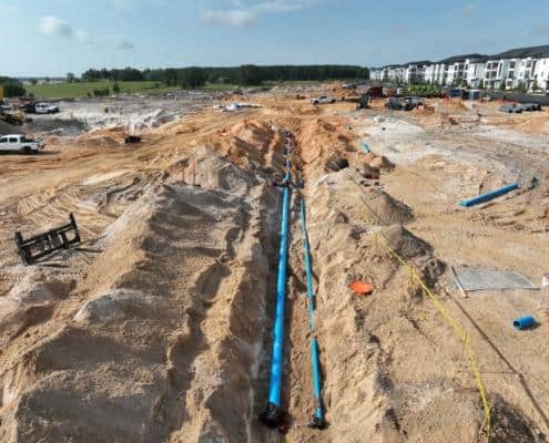 Underground plumbing installation at a residential or commercial construction site in Florida, showcasing site development and infrastructure setup.