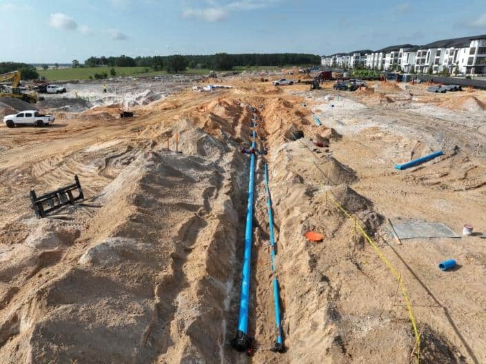 Underground plumbing installation at a residential or commercial construction site in Florida, showcasing site development and infrastructure setup.
