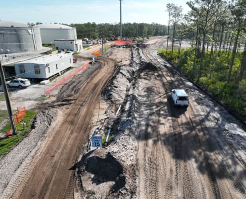 Construction site of commercial development with dirt roads, equipment, and nearby existing infrastructure, showcasing site preparation and development services.