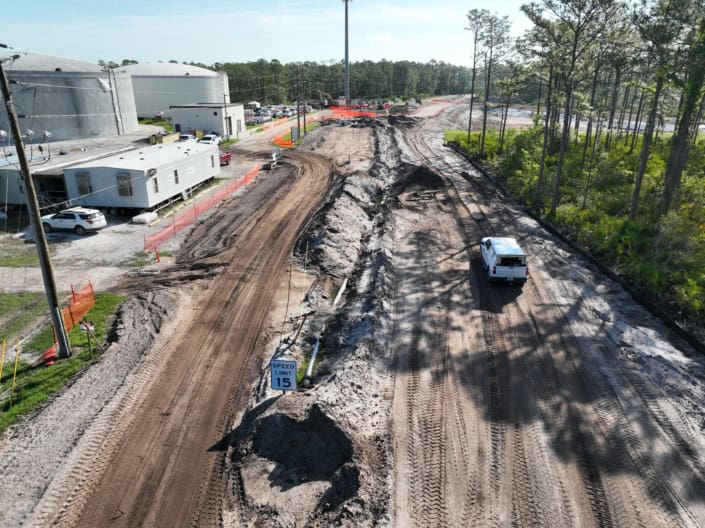 Construction site of commercial development with dirt roads, equipment, and nearby existing infrastructure, showcasing site preparation and development services.