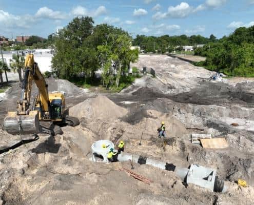 Heavy construction site with excavator and workers installing underground utilities, preparing the land for development, showcasing site development services.