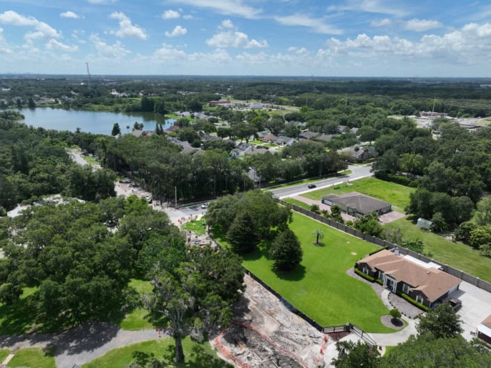 Aerial view of residential neighborhood with ongoing site development projects and lush greenery, showcasing landscape design, infrastructure improvements, and urban planning efforts.