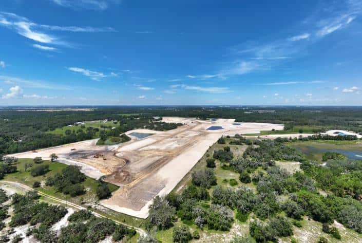 Aerial view of site development for commercial or industrial construction with land clearing, grading, and water features.