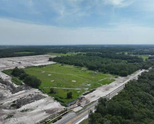 Aerial view of a land development site with cleared areas and construction progress, showcasing site development and infrastructure planning for future projects.