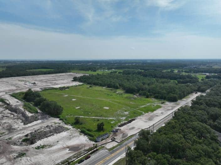 Aerial view of a land development site with cleared areas and construction progress, showcasing site development and infrastructure planning for future projects.