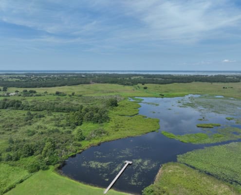 Lush green wetlands with water bodies and surrounding fields, showcasing site development potential and natural landscape in Florida.