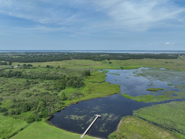 Lush green wetlands with water bodies and surrounding fields, showcasing site development potential and natural landscape in Florida.
