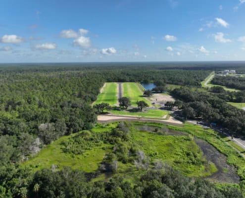 Aerial view of land development site surrounded by lush greenery and dense forest for strategic site development and infrastructure planning.