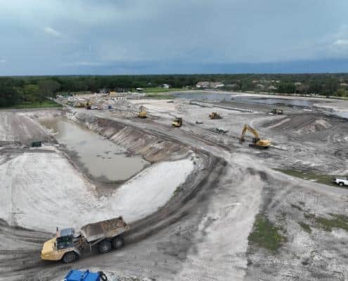 Heavy construction site with earthmoving equipment and drainage ponds during a land development project for site construction.