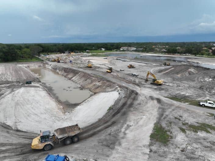 Heavy construction site with earthmoving equipment and drainage ponds during a land development project for site construction.