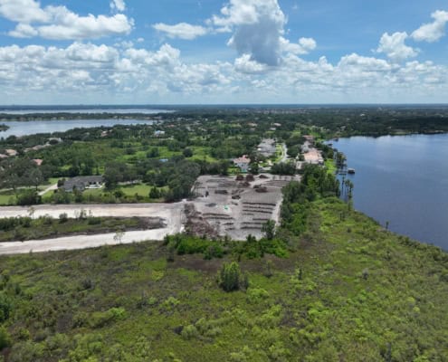 Aerial view of land development and site preparation near a water body, showcasing progress in site development for residential or commercial projects by SDC Site Development.