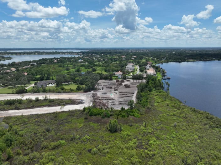 Aerial view of land development and site preparation near a water body, showcasing progress in site development for residential or commercial projects by SDC Site Development.